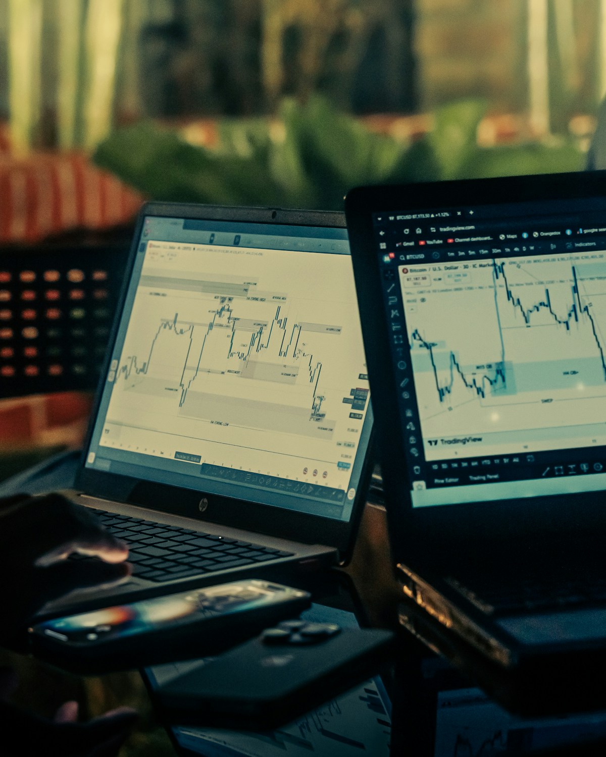 Two laptops displaying stock market candlestick charts in a browser